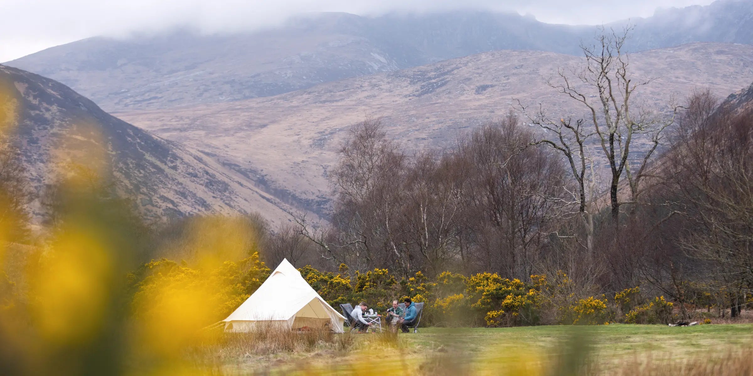 Campers sat outside a cotton teepee tent in Scotland