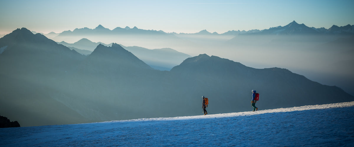 Two people walking on a glacier