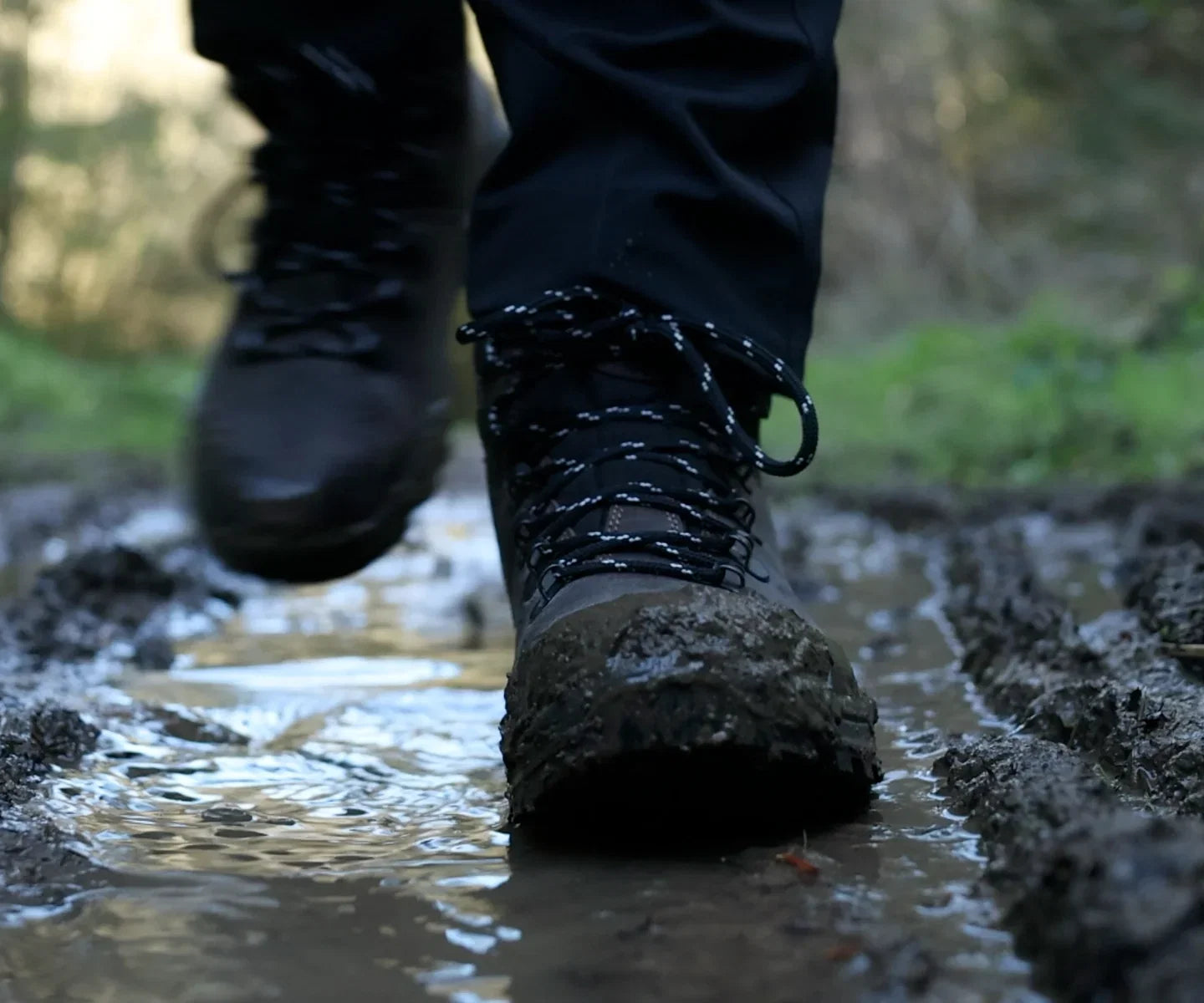 Waterproof hiking boot splashing through wet mud