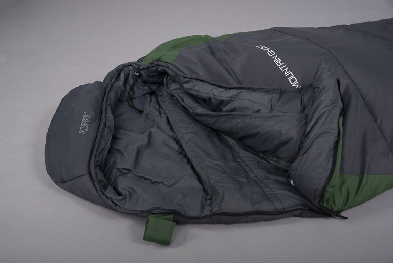 The hood end of a Mountain Ghost 200 synthetic 2 season sleeping bag with the zip open in green and grey laid on the floor on a grey background