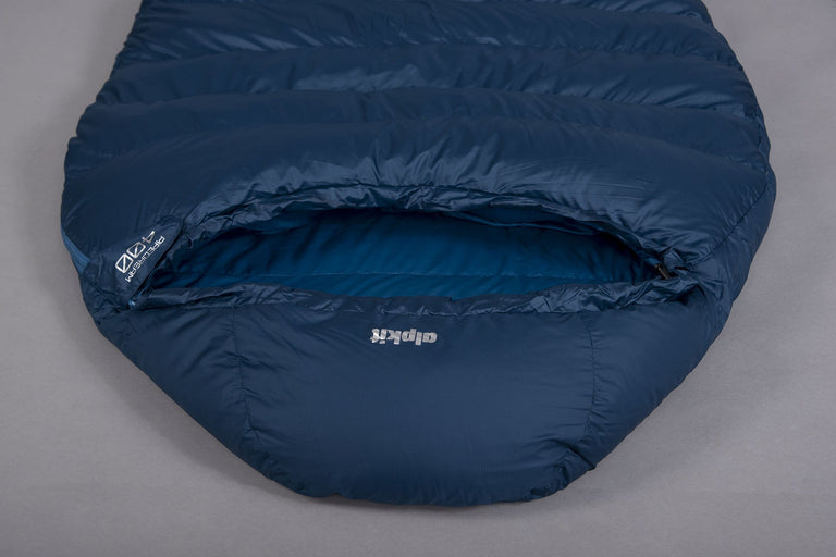 The hood of a Pipedream 400 lightweight 3 season sleeping bag in blue laid on the floor upside down on a grey background