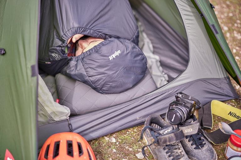 A man sleeping in a bikepacking tent in an ultralight PrimaLoft® sleeping bag - action - closed