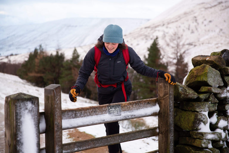 A woman crossing a style in a dark grey insulated jacket - action