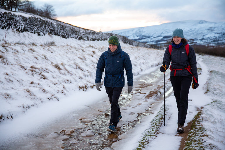 A man and a woman hiking along a lane in the snowy Peak District - action|hw