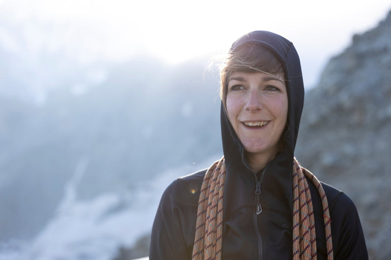 A woman coiling rope in the French Alps wearing a black hooded fleece jacket - action