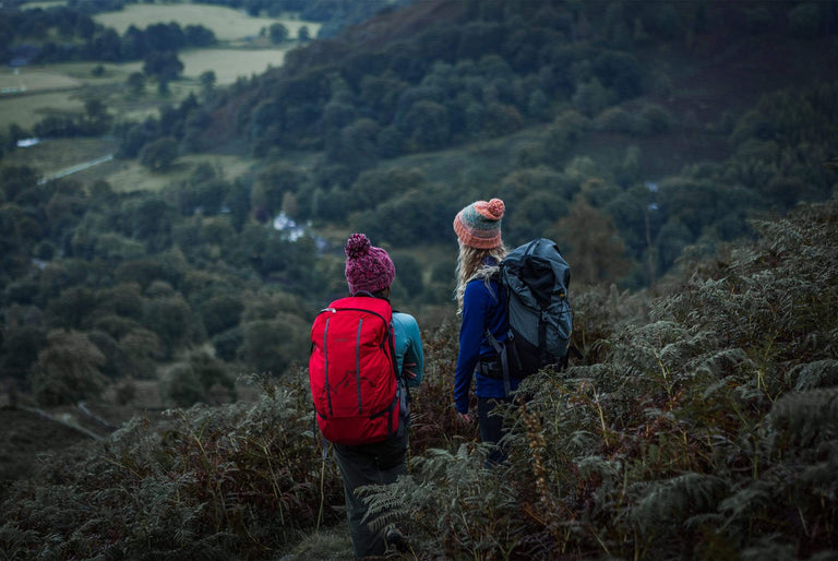 Two women exploring the hills wearing packs - action